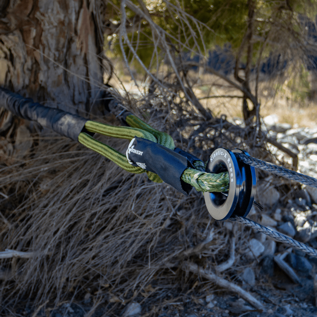 Close-up of a Kinetic-X soft shackle and pulley system wrapped around a tree for off-road winching and recovery operations.