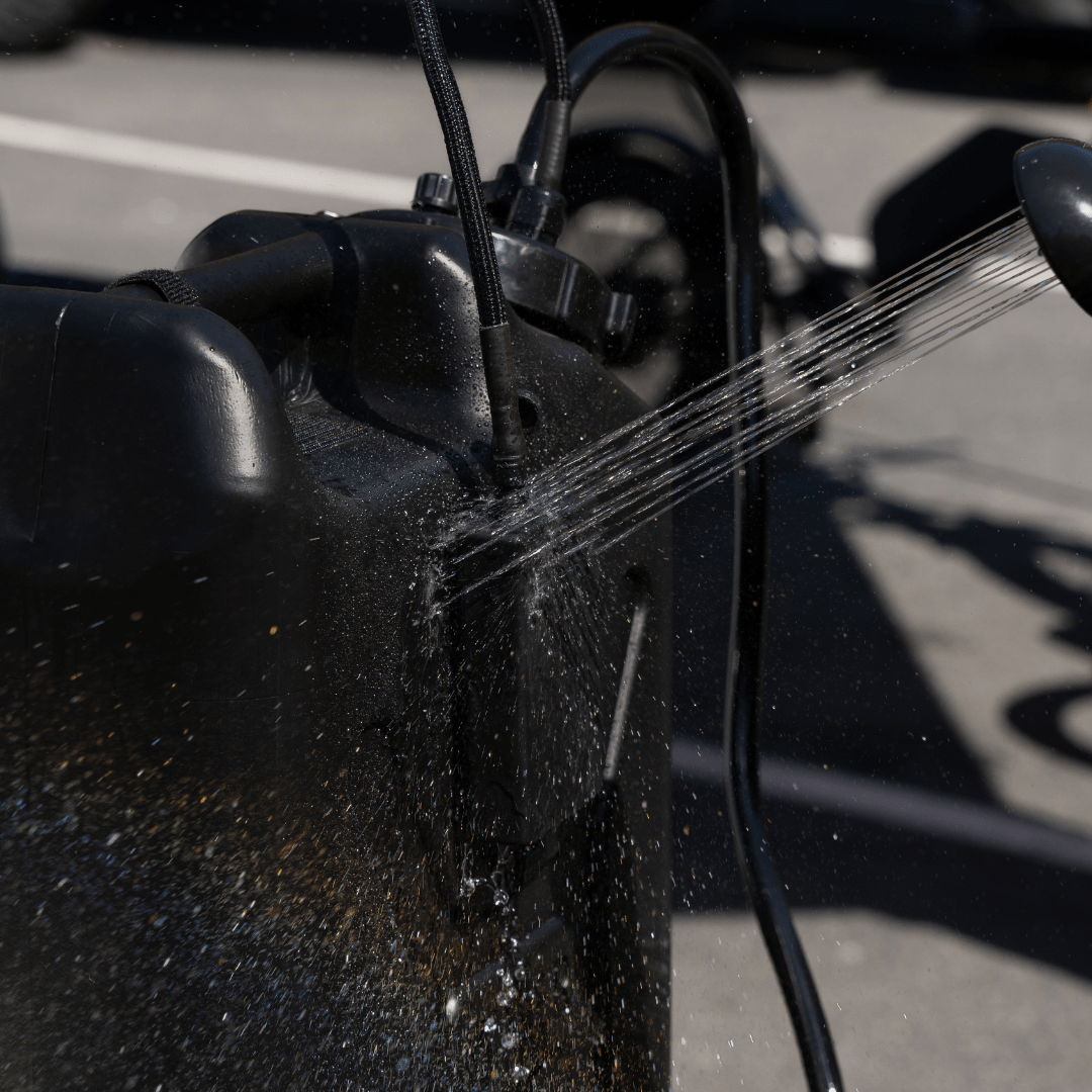 TrailWash battery pack mounted on a black Scepter canister being sprayed with water to demonstrate waterproof durability